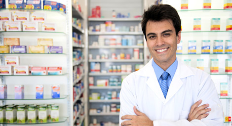A male pharmacist stood with his arms crossed in front of medication shelves