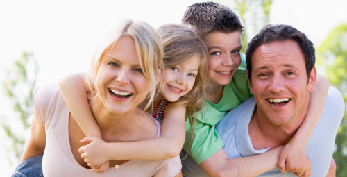 Smiling parents giving their children a piggy back
